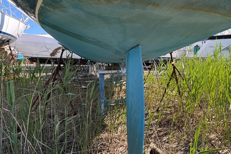 Slide: The Image of Catalina 320 sailboat keel, 1998 model, on dry land surrounded by grass. - 8