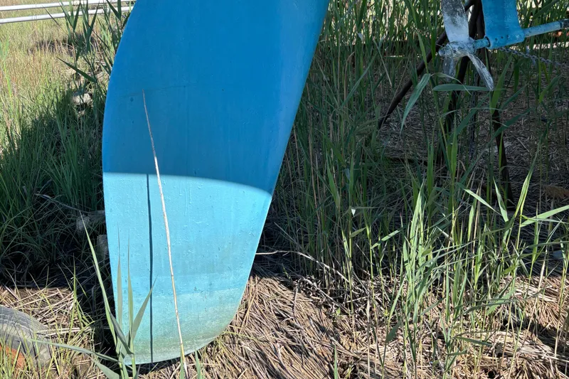 Slide: The Image of Blue keel of a 1998 Catalina 320 sailboat surrounded by grass. - 9