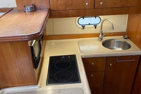 Slide: The Image of 2003 Cruisers Yachts 3750 Motoryacht kitchen with stove, sink, and wooden cabinetry. - 44