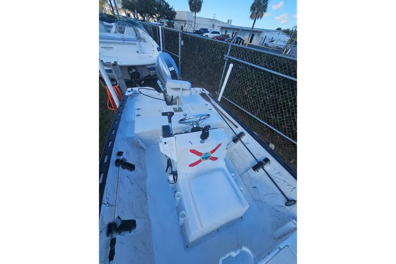 Slide: The Image of 1999 Aqua Force Fish Hawk boat with fishing gear, parked near a fence. - 6