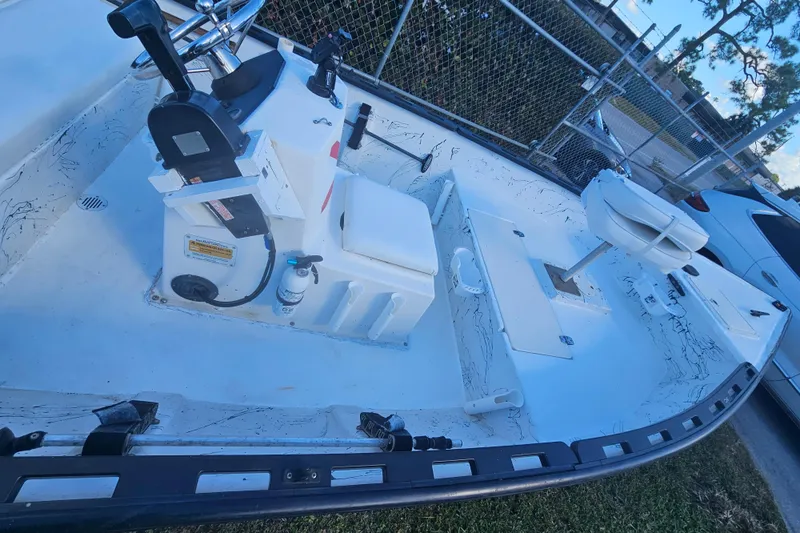 Slide: The Image of 1999 Aqua Force Fish Hawk boat interior with seating and control panel, parked near a fence. - 7