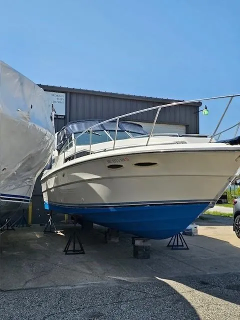 The Image of 1988 Sea Ray 340 Sundancer boat on stands, blue hull, outdoor storage. - 1