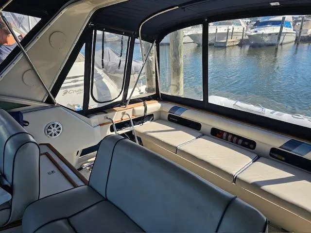 Slide: The Image of 1988 Sea Ray 340 Sundancer interior with seating, windows, and marina view. - 11