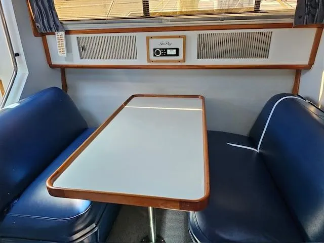 Slide: The Image of 1988 Sea Ray 340 Sundancer interior with blue seating and a wooden table. - 17