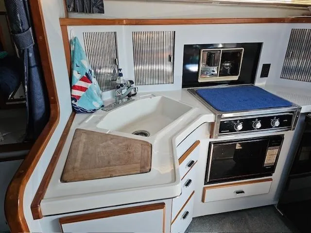 Slide: The Image of 1988 Sea Ray 340 Sundancer kitchen with sink, stove, and cutting board. - 19