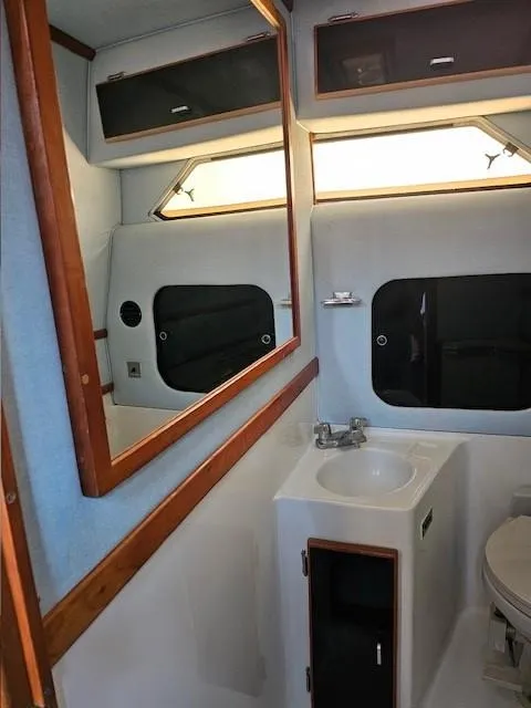 Slide: The Image of 1988 Sea Ray 340 Sundancer bathroom with sink, mirror, and storage cabinets. - 22