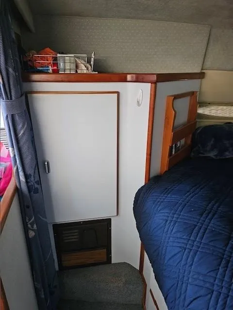 Slide: The Image of 1988 Sea Ray 340 Sundancer cabin interior with blue bedding and storage cabinet. - 26