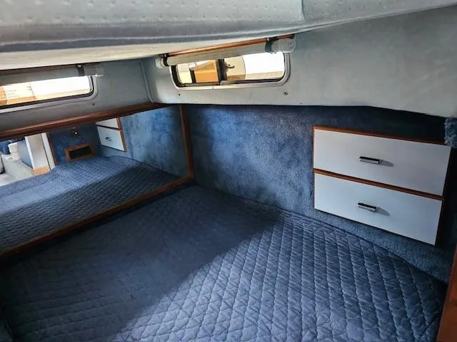 Slide: The Image of 1988 Sea Ray 340 Sundancer cabin interior with blue carpet, drawers, and windows. - 29