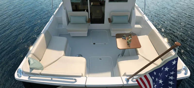 Slide: The Image of 2026 Back Cove 412 yacht deck with seating, table, and American flag on calm water. - 8