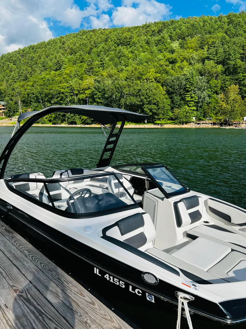 Slide: The Image of 2022 Yamaha Boats 195 S docked on a scenic lake with lush green hills. - 4