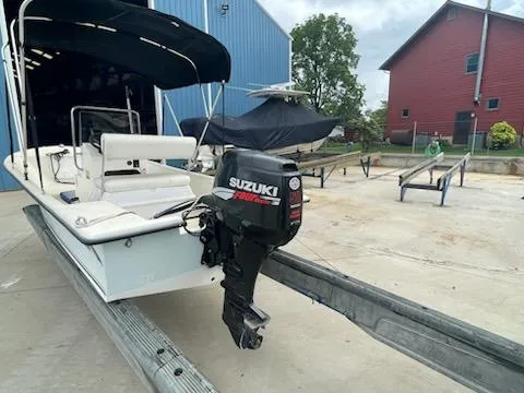 Slide: The Image of 2009 May-Craft 1700 Skiff with Suzuki outboard motor on trailer, near blue and red buildings. - 5