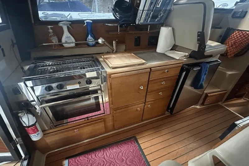 Slide: The Image of 2019 Ranger R27 LE boat kitchen with stove, wooden cabinets, and countertop accessories. - 10