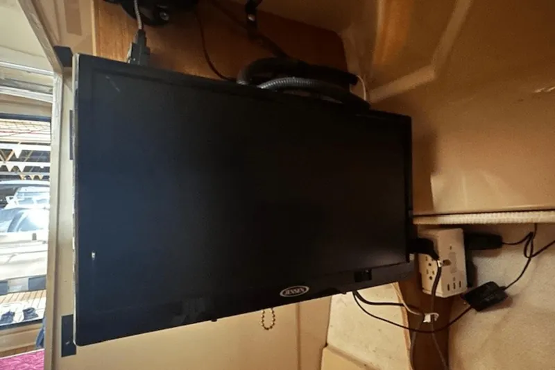 Slide: The Image of Mounted TV inside 2019 Ranger R27 LE boat cabin with visible cables and power outlet. - 26