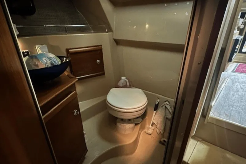 Slide: The Image of 2019 Ranger R27 LE boat bathroom with toilet, sink, and wooden cabinetry. - 27
