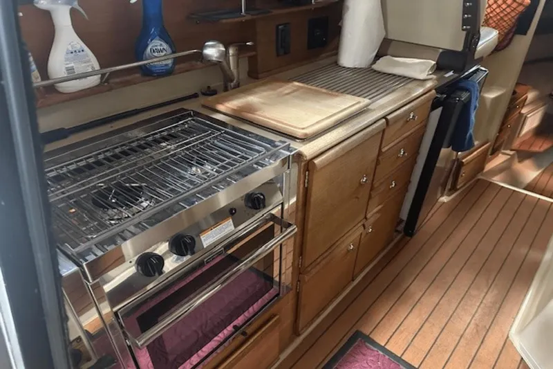 Slide: The Image of Compact kitchen in 2019 Ranger R27 LE boat with stove, wooden cabinets, and cleaning supplies. - 9