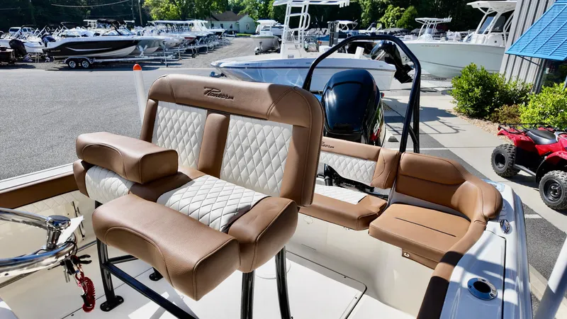 Slide: The Image of 2025 Pioneer 222 Islander boat with tan and white seating, docked in a marina. - 16