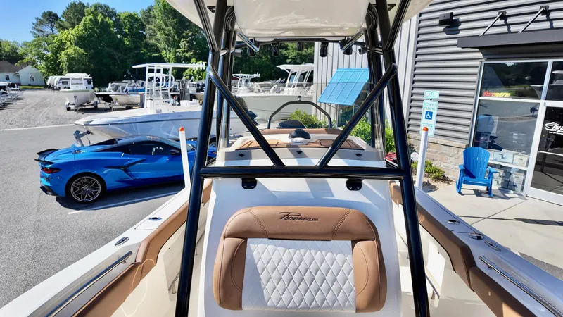 Slide: The Image of 2025 Pioneer 222 Islander boat with luxury seating, parked near a blue sports car. - 17