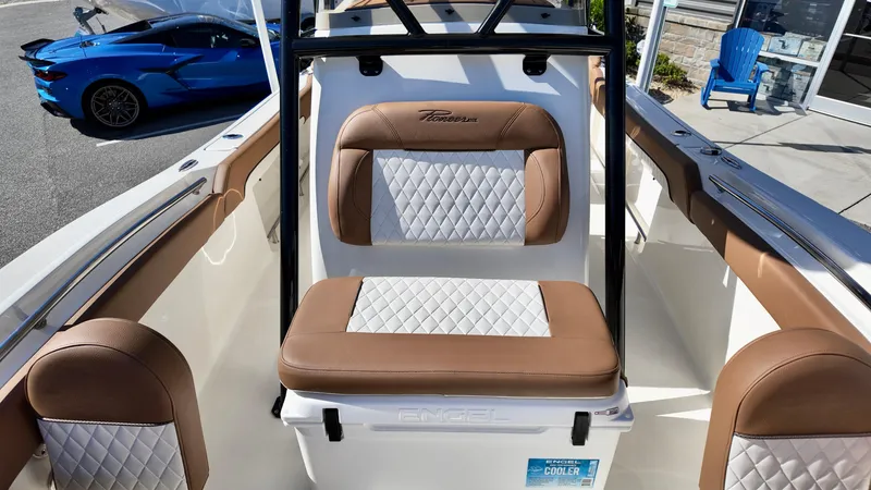 Slide: The Image of 2025 Pioneer 222 Islander boat interior with brown and white seating, parked near a blue car. - 18