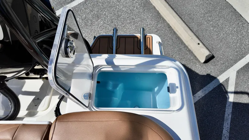 Slide: The Image of Open storage compartment on 2025 Pioneer 222 Islander boat, featuring brown seating and rod holders. - 22