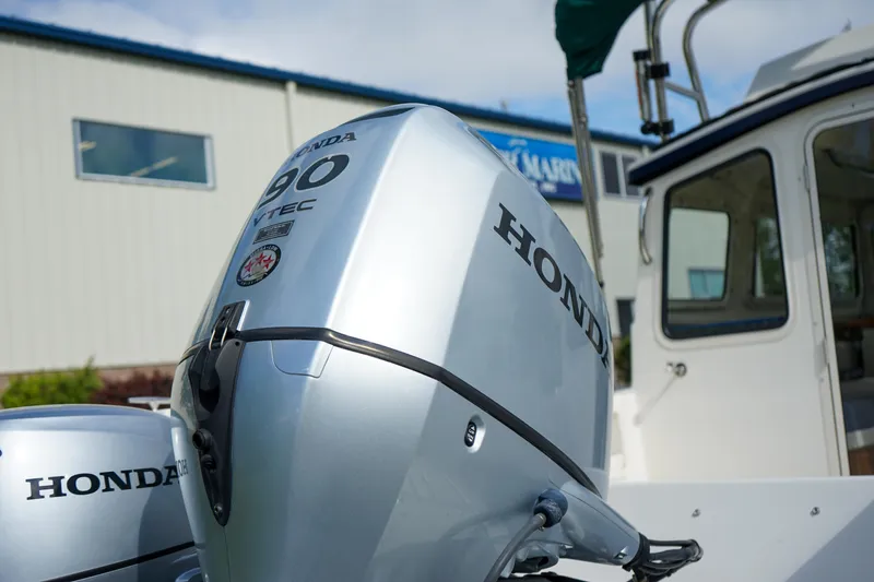 Slide: The Image of 2016 C-Dory 22' Cruiser with Honda outboard motor, parked near a building. - 17