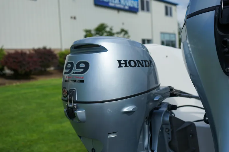 Slide: The Image of Honda 9.9 outboard motor on a 2016 C-Dory 22' Cruiser, parked near a building. - 18