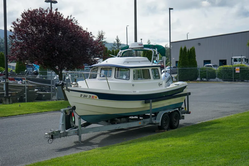 Slide: The Image of 2016 C-Dory 22' Cruiser on trailer in parking lot, surrounded by greenery. - 19
