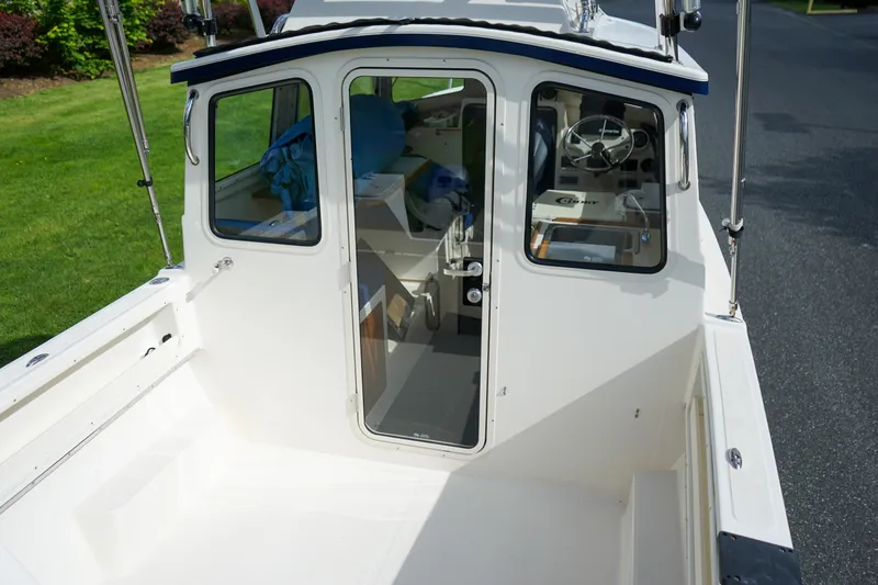 Slide: The Image of 2016 C-Dory 22' Cruiser boat cockpit with cabin view, steering wheel, and outdoor seating. - 5