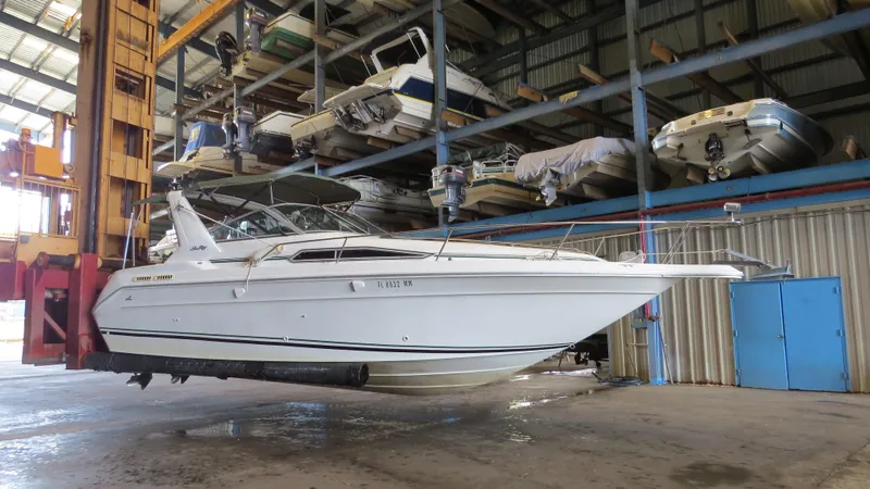 The Image of 1989 Sea Ray Sundancer 280 in a boat storage facility, elevated for maintenance. - 0