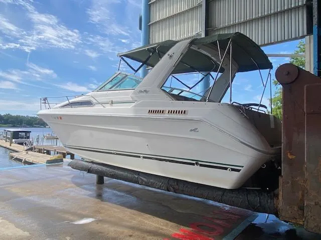 Slide: The Image of 1989 Sea Ray Sundancer 280 boat on lift, under blue sky, near dock. - 1