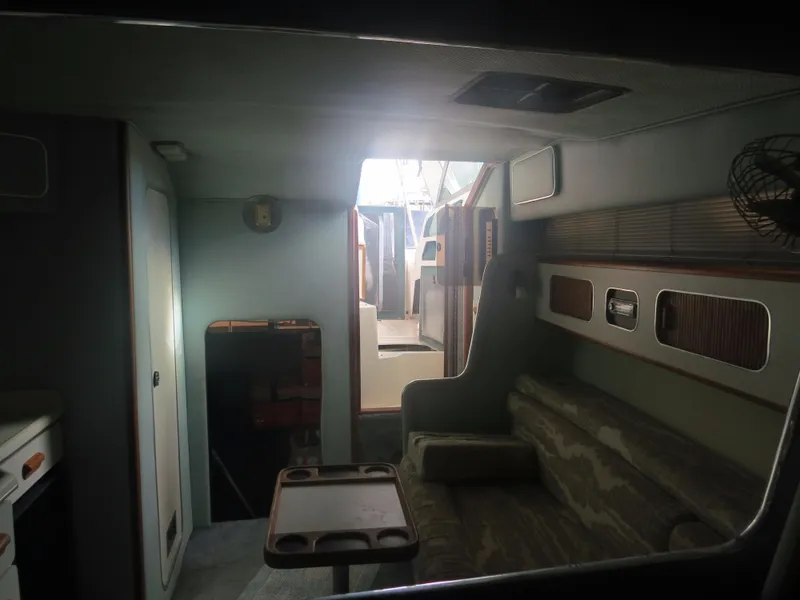Slide: The Image of 1989 Sea Ray Sundancer 280 cabin interior with seating and table, showcasing vintage design. - 17