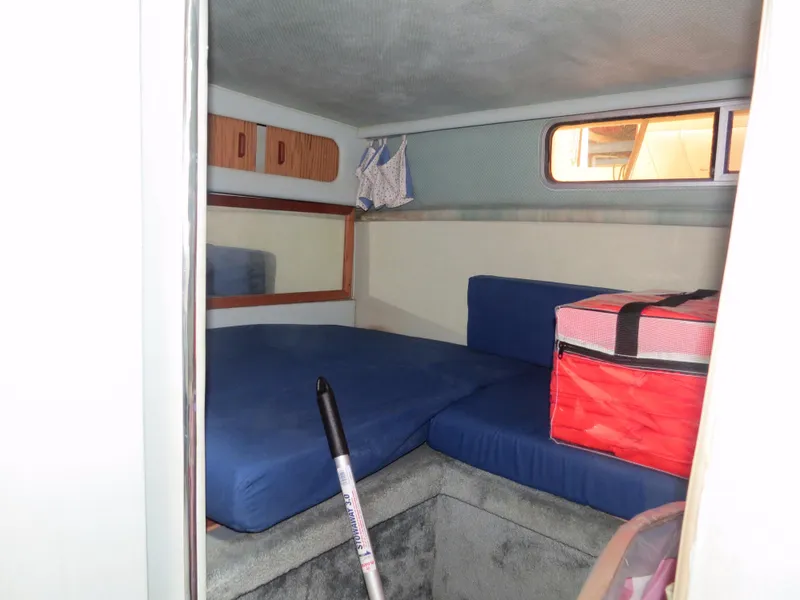 Slide: The Image of 1989 Sea Ray Sundancer 280 cabin interior with blue cushions and storage compartments. - 20