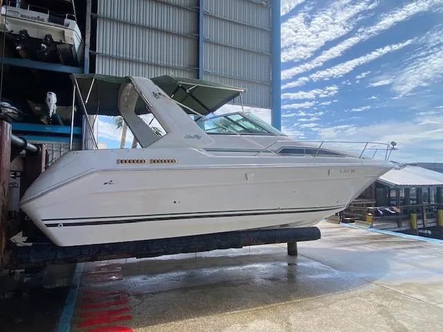 Slide: The Image of 1989 Sea Ray Sundancer 280 boat in dry dock, under a clear blue sky. - 27