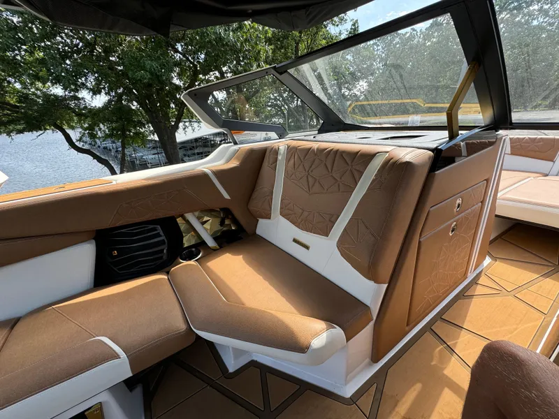 Slide: The Image of 2024 Nautique G25 Paragon interior with luxurious brown and white seating, lake view. - 14
