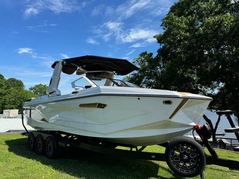 Slide: The Image of 2024 Nautique G25 Paragon boat on trailer, parked on grass under blue sky. - 3