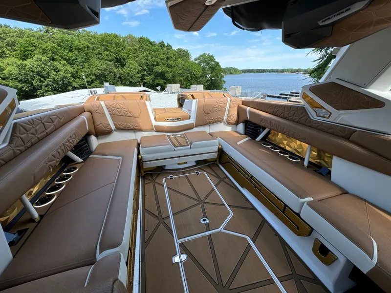 Slide: The Image of Luxurious interior of 2024 Nautique G25 Paragon boat with brown seating and scenic lake view. - 6