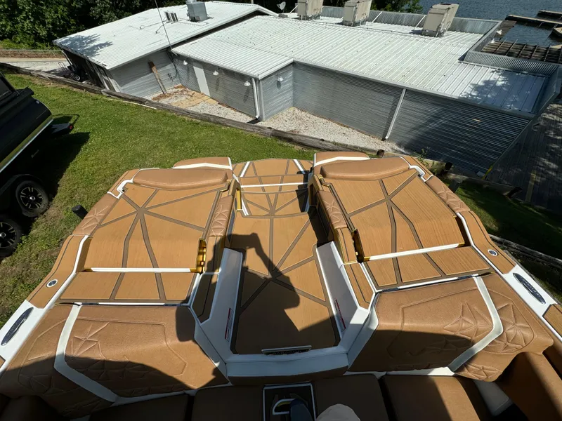 Slide: The Image of 2024 Nautique G25 Paragon boat with tan upholstery, viewed from above, near a building. - 7