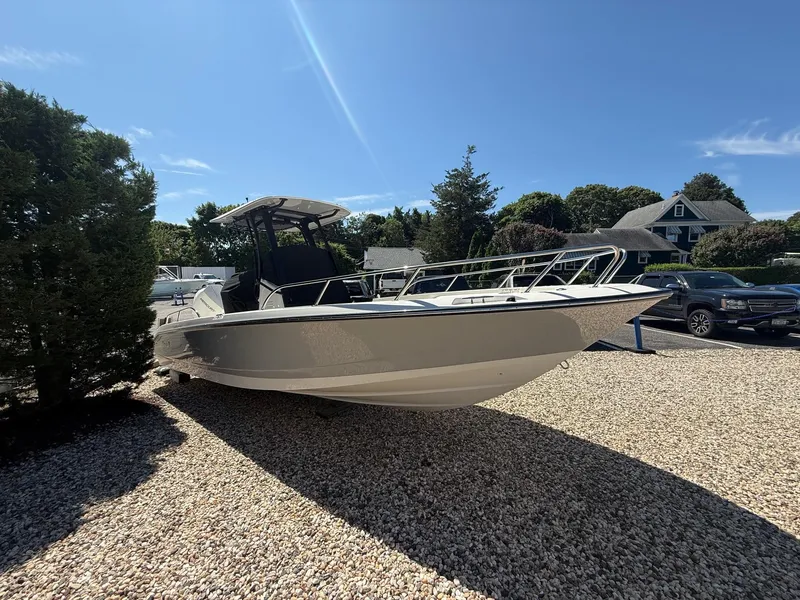 Slide: The Image of 2025 Boston Whaler 250 Dauntless boat on gravel lot under clear blue sky. - 1