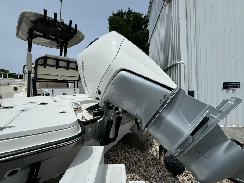 Slide: The Image of 2025 Boston Whaler 250 Dauntless boat with powerful outboard motor, docked near a metal building. - 14