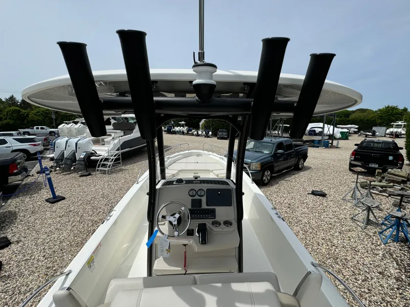 Slide: The Image of 2025 Boston Whaler 250 Dauntless boat interior with console and rod holders, parked outdoors. - 15
