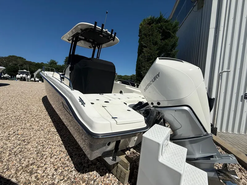 Slide: The Image of 2025 Boston Whaler 250 Dauntless boat with Mercury engine, parked outdoors on gravel. - 2