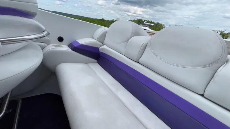 Slide: The Image of 2003 Baja 33 Outlaw boat interior with white and purple seating under cloudy sky. - 11