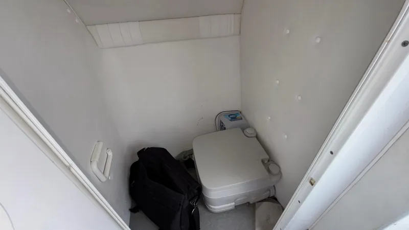 Slide: The Image of Compact bathroom in a 2003 Baja 33 Outlaw boat, featuring a portable toilet. - 31