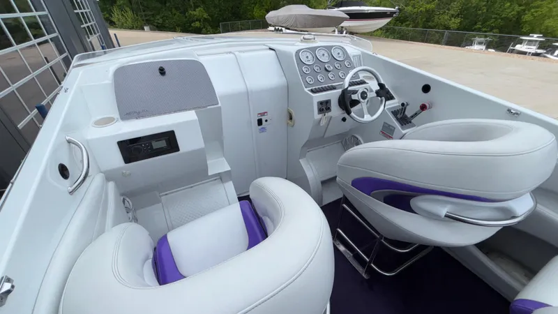 Slide: The Image of 2003 Baja 33 Outlaw boat interior with white and purple seating, dashboard, and steering wheel. - 36