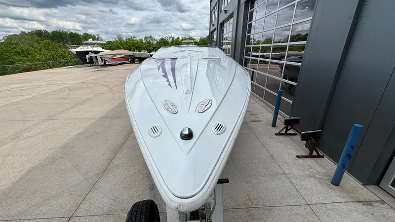 Slide: The Image of 2003 Baja 33 Outlaw boat parked outside a modern building, showcasing sleek design. - 4