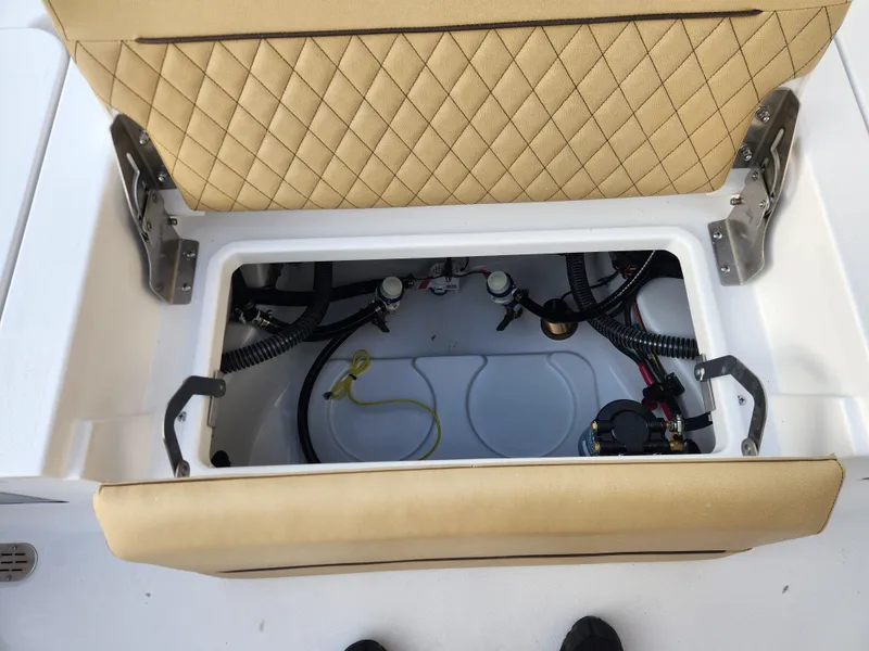 Slide: The Image of 2025 Sportsman Masters 247OE Bay Boat storage compartment with tan cushioned lid and visible wiring. - 21
