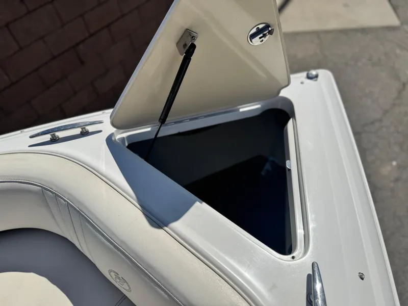 Slide: The Image of Open storage compartment on a 2006 Cobalt 232 boat, featuring white cushioned seating. - 17