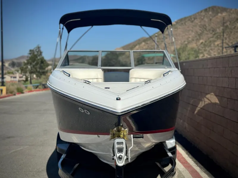 Slide: The Image of 2006 Cobalt 232 boat with canopy, parked on a sunny day near a brick wall. - 2