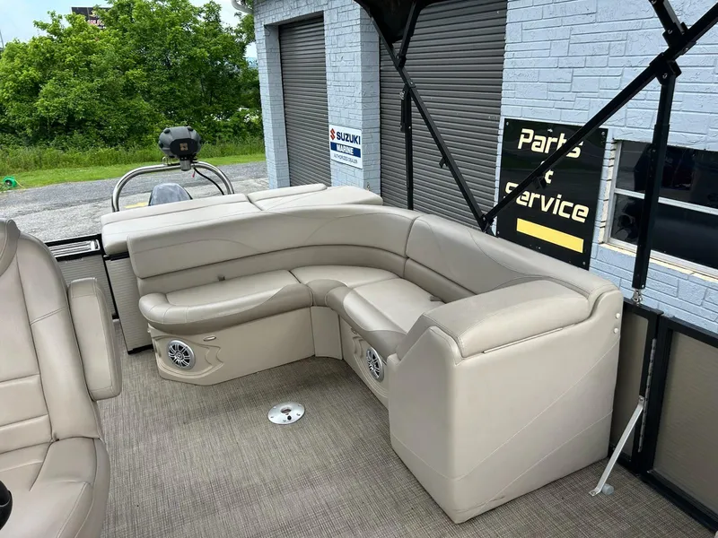 Slide: The Image of 2018 Avalon 2485 LSZ Cruise boat interior with beige seating and speakers, parked near service area. - 8