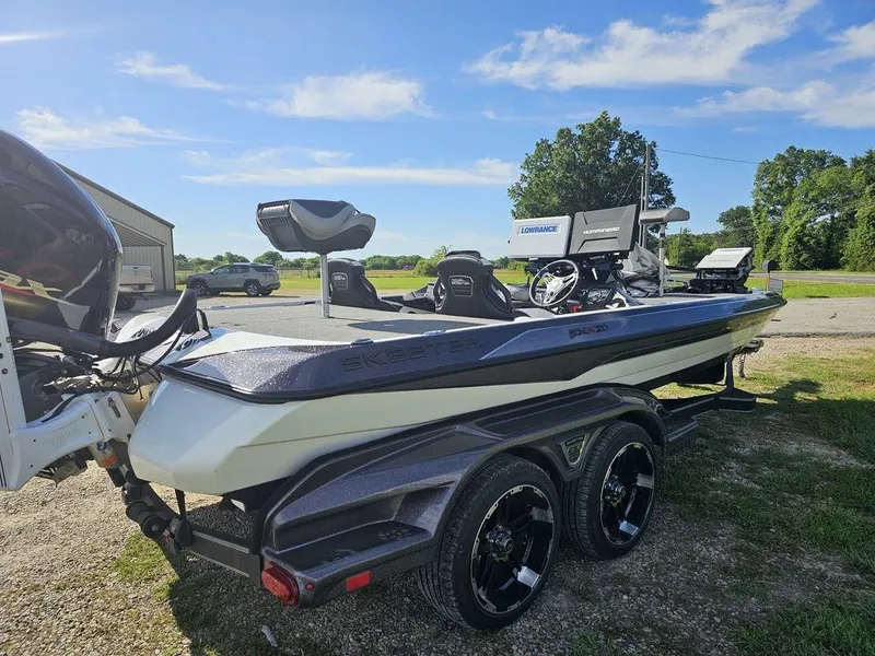 Slide: The Image of 2020 Skeeter FXR21 bass boat on trailer, parked outdoors under a clear blue sky. - 8
