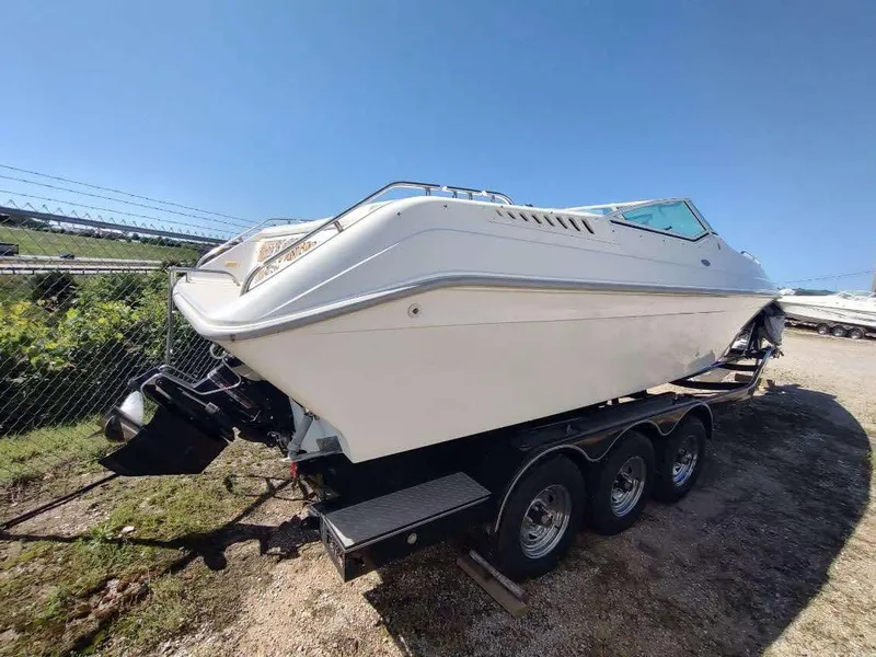 Slide: The Image of 1998 Envision 2900 Combo boat on a trailer, parked outdoors under clear blue sky. - 32